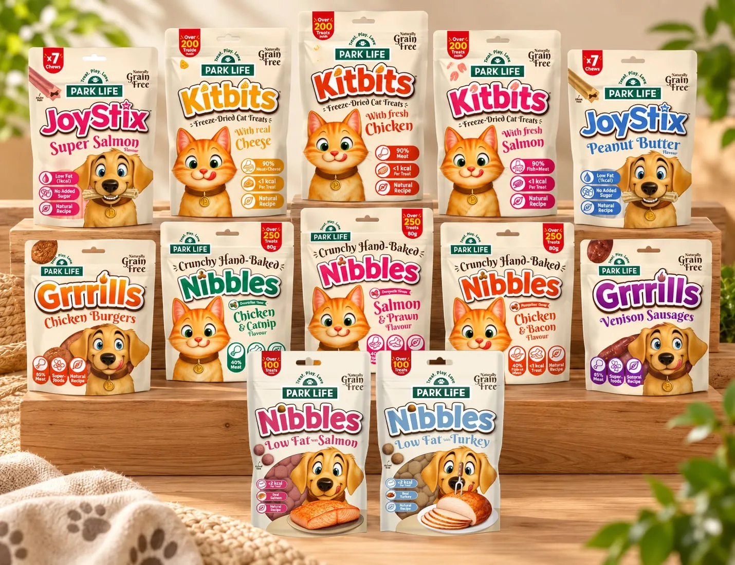 Park Life pet treat pouches on wooden steps: JoyStix chews, Kitbits freeze-dried cat treats, Grrrills, and Crunchy Hand-Baked and Low Fat Nibbles.